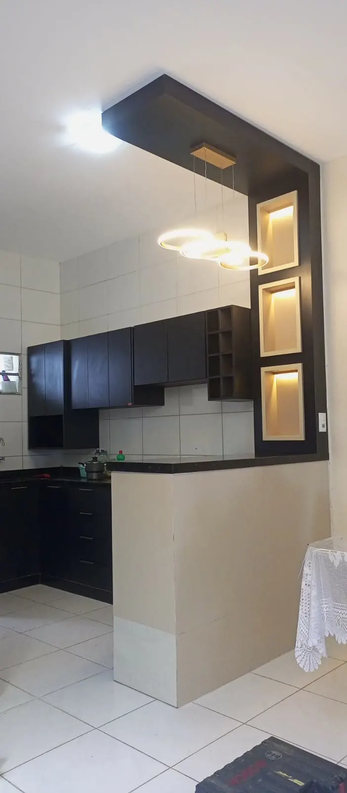 Cozinha preta com balcão e coluna de nichos iluminados