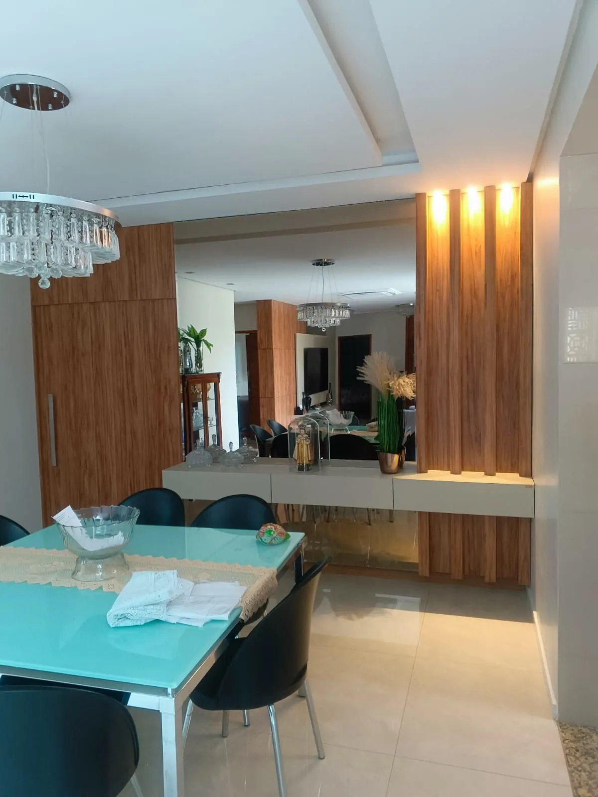 Sala de jantar com painéis em madeira e aparador iluminado